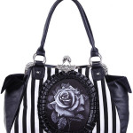 Bolso gótico con rosa negra y rayas Bolso hecho de tela con rayas blancas y negras y decorado con cuero sintético. En el centro hay una rosa negra rodeada de un marco de piel sintética. En los lados hay dos amplios bolsillos hechos de imitación de cuero. En el interior hay un forro negro y suave con dos bolsillos. Uno grande con cremallera y otro más pequeña.